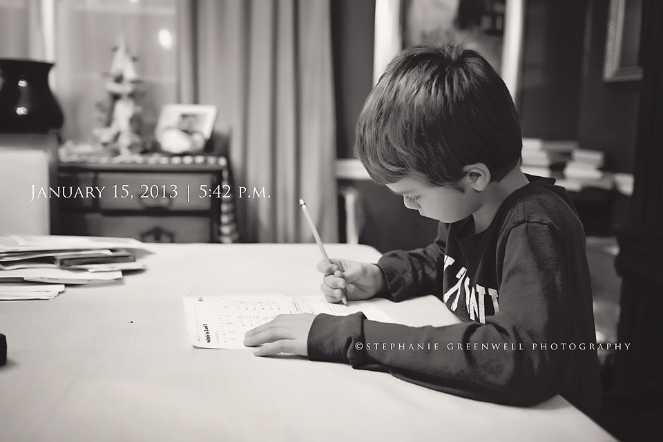 boy doing homework at table holding pencil stephanie greenwell